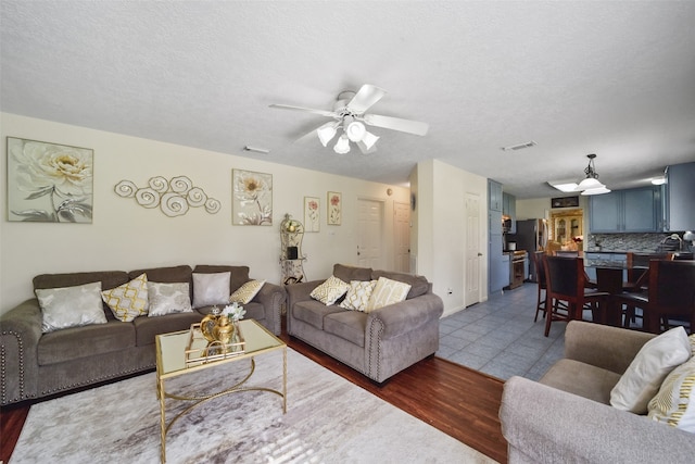 living room with ceiling fan, wood-type flooring, and a textured ceiling