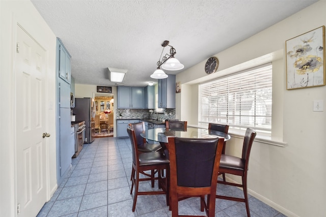 dining area featuring light tile patterned floors, a textured ceiling, and sink