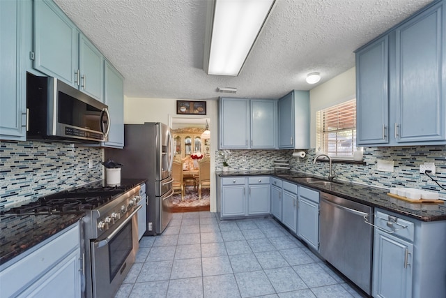 kitchen with backsplash, blue cabinetry, sink, and appliances with stainless steel finishes