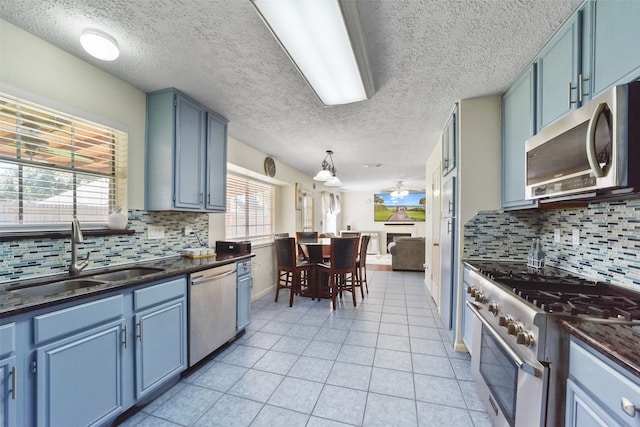 kitchen with sink, blue cabinets, a textured ceiling, decorative backsplash, and appliances with stainless steel finishes