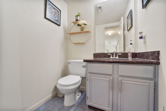 bathroom with tile patterned floors, vanity, a textured ceiling, and toilet