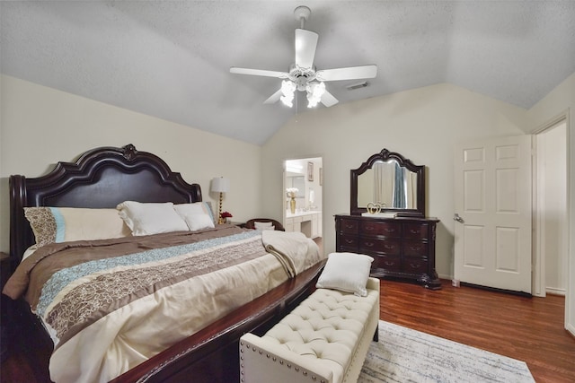 bedroom with ensuite bathroom, a textured ceiling, vaulted ceiling, ceiling fan, and dark hardwood / wood-style floors