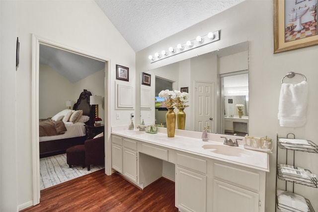 bathroom with vaulted ceiling, vanity, wood-type flooring, and a textured ceiling