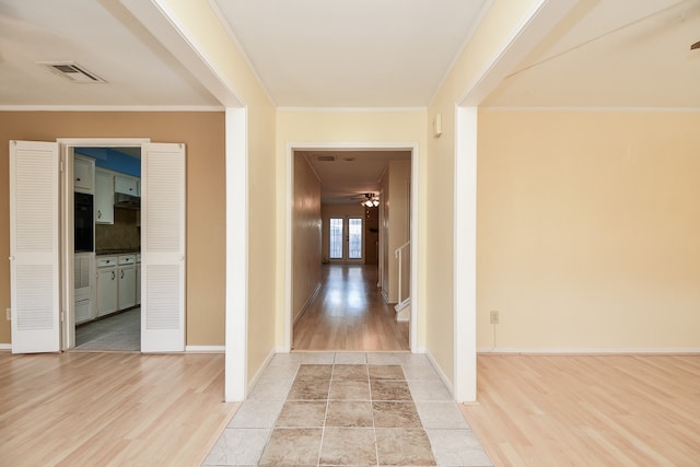 hallway featuring crown molding, light hardwood / wood-style flooring, and french doors