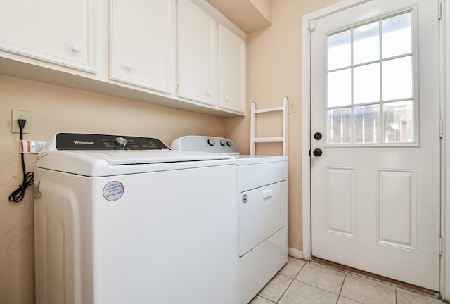 laundry area featuring cabinets, light tile patterned floors, and washing machine and dryer