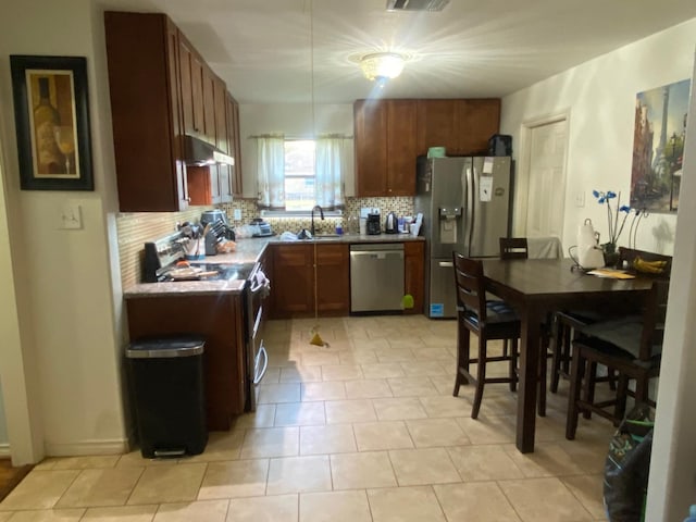 kitchen with backsplash, sink, light tile patterned floors, and stainless steel appliances