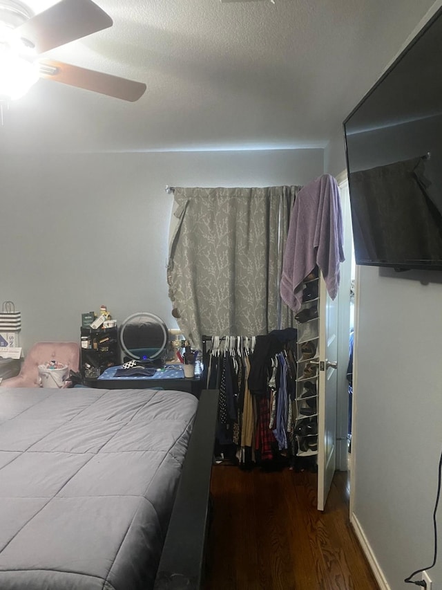 bedroom with ceiling fan, dark wood-type flooring, and a textured ceiling