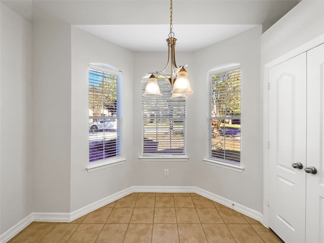 unfurnished dining area featuring light tile patterned floors, a wealth of natural light, and an inviting chandelier