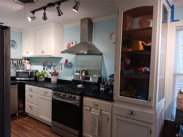 kitchen with appliances with stainless steel finishes, wall chimney exhaust hood, dark wood-type flooring, crown molding, and white cabinets