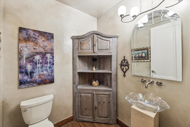 bathroom featuring wood-type flooring, an inviting chandelier, and toilet