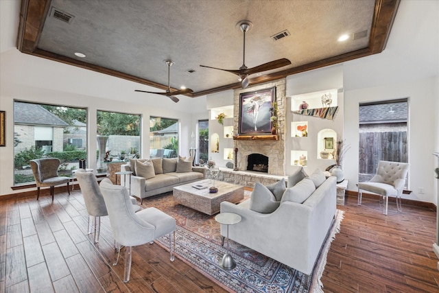 living room featuring ornamental molding, ceiling fan, a fireplace, a tray ceiling, and a textured ceiling