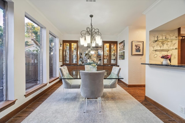 dining room with crown molding, a notable chandelier, and dark wood-type flooring