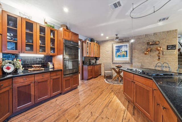 kitchen featuring black double oven, gas cooktop, light hardwood / wood-style floors, decorative backsplash, and ceiling fan