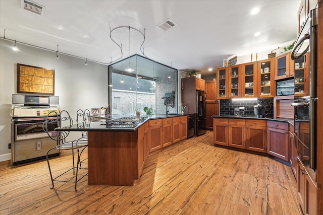 kitchen featuring a breakfast bar, light wood-type flooring, a center island, and decorative backsplash