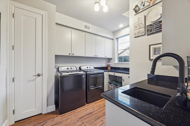 kitchen featuring independent washer and dryer, hardwood / wood-style flooring, white cabinetry, dark stone countertops, and sink