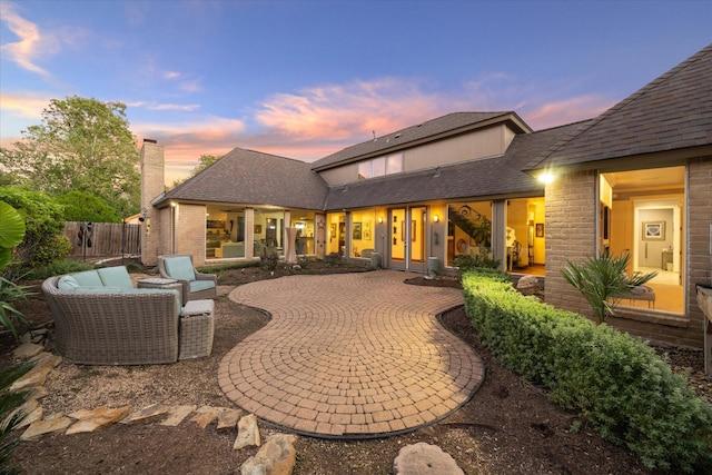 back house at dusk featuring a patio and outdoor lounge area