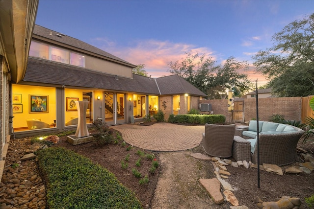 back house at dusk with a patio and central AC