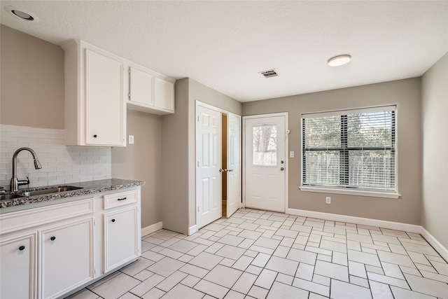 kitchen featuring decorative backsplash, a textured ceiling, sink, stone countertops, and white cabinetry