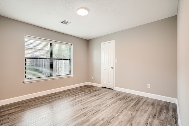 spare room with a textured ceiling and light wood-type flooring