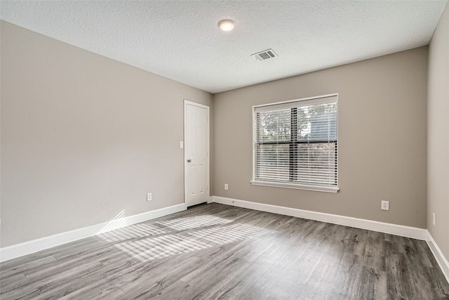 empty room with wood-type flooring and a textured ceiling