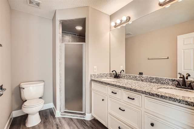 bathroom with vanity, a shower with shower door, a textured ceiling, and wood-type flooring