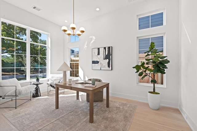 office space featuring light wood-type flooring and a notable chandelier