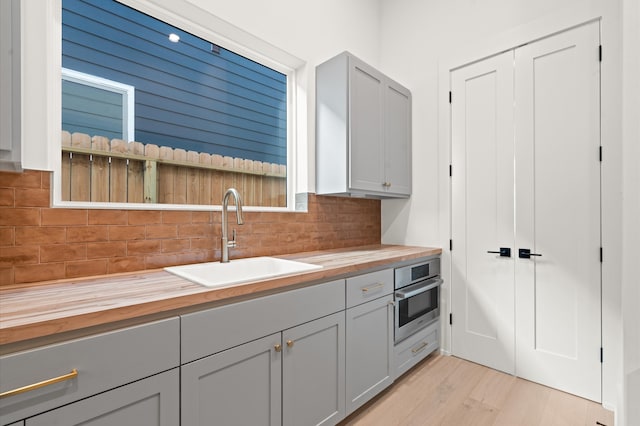 kitchen featuring backsplash, oven, butcher block counters, and sink