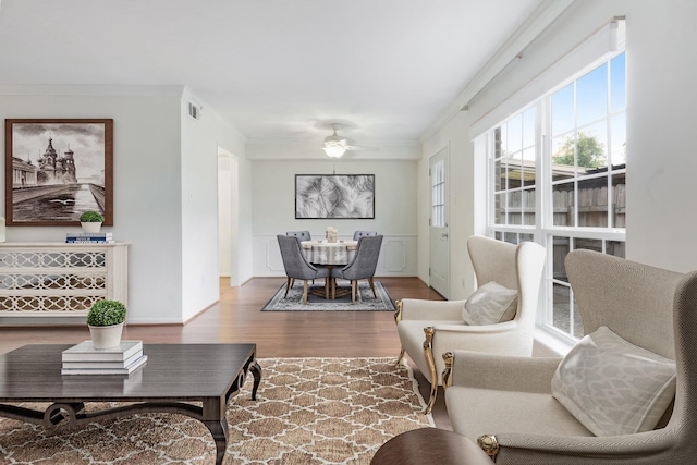 living room featuring hardwood / wood-style flooring, ceiling fan, and crown molding