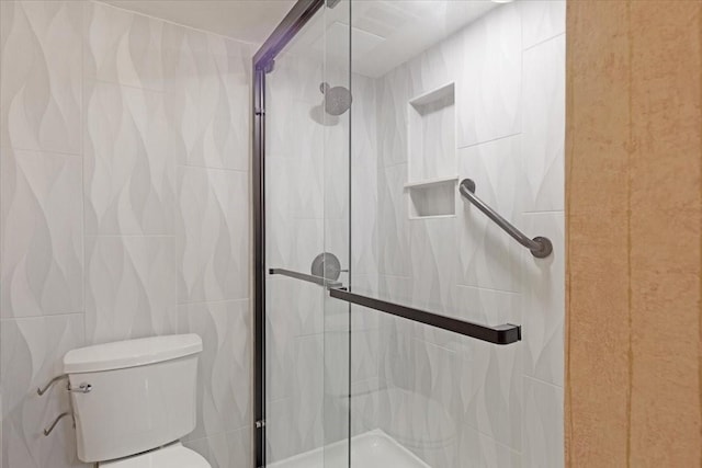 bathroom with an enclosed shower, toilet, and tile walls