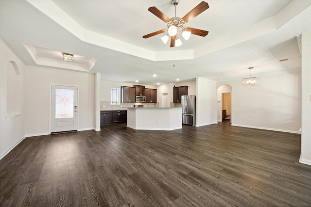 unfurnished living room with dark hardwood / wood-style flooring, ornamental molding, a raised ceiling, and ceiling fan