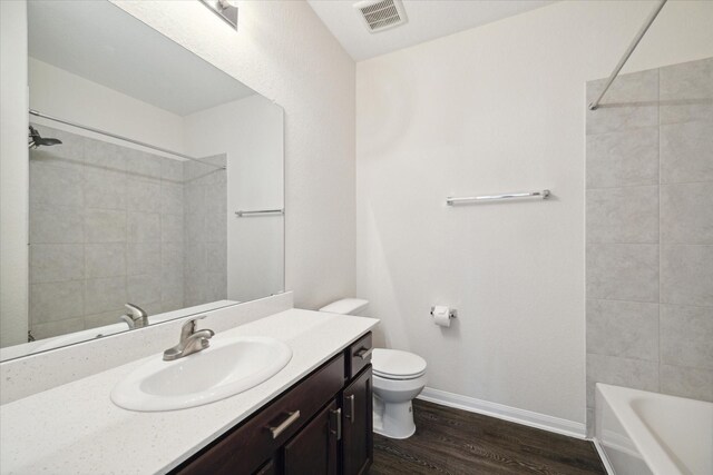 full bathroom featuring tiled shower / bath, hardwood / wood-style floors, vanity, and toilet