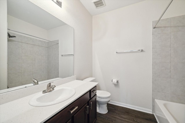 full bathroom featuring hardwood / wood-style flooring, tiled shower / bath, vanity, and toilet