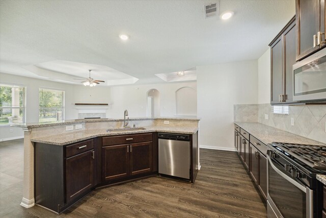 kitchen featuring light stone countertops, appliances with stainless steel finishes, dark hardwood / wood-style flooring, dark brown cabinetry, and sink