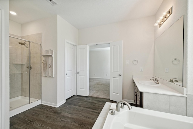 bathroom featuring wood-type flooring, plus walk in shower, and vanity