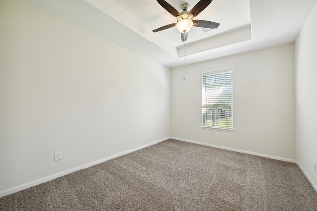 spare room featuring carpet floors, a raised ceiling, and ceiling fan