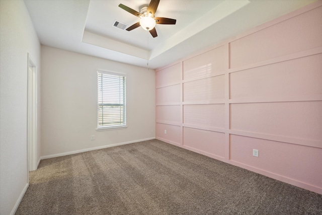 carpeted spare room with ceiling fan and a raised ceiling