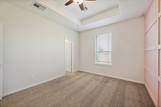 carpeted empty room with a tray ceiling and ceiling fan