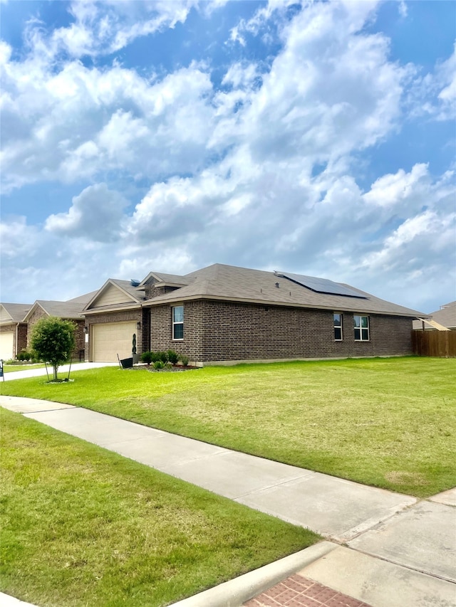 ranch-style home featuring solar panels, a front lawn, and a garage