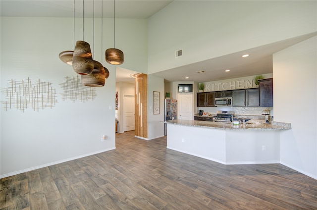 kitchen featuring appliances with stainless steel finishes, dark hardwood / wood-style floors, light stone counters, and dark brown cabinets