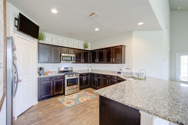 kitchen featuring sink, dark brown cabinetry, light hardwood / wood-style floors, kitchen peninsula, and stainless steel appliances