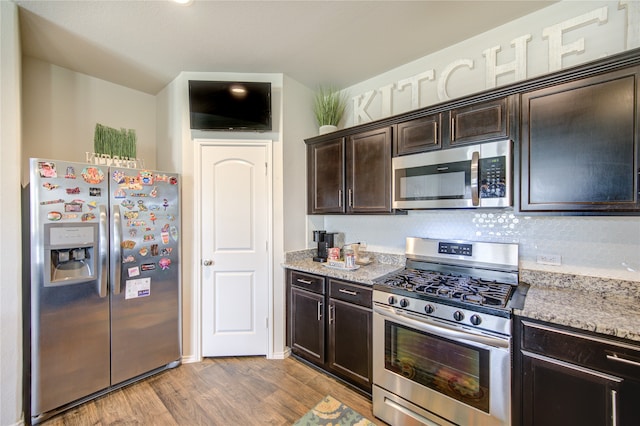 kitchen featuring light stone countertops, appliances with stainless steel finishes, decorative backsplash, dark brown cabinets, and light hardwood / wood-style floors