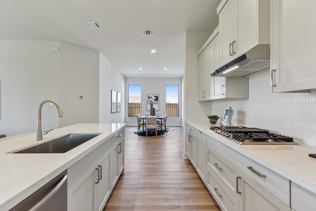 kitchen with sink, appliances with stainless steel finishes, tasteful backsplash, light hardwood / wood-style floors, and white cabinetry