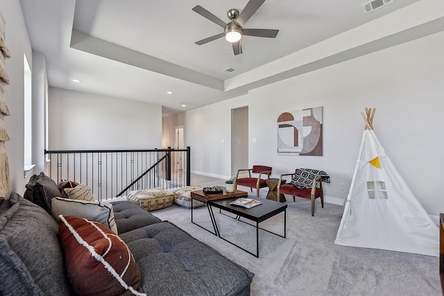 living room with a tray ceiling, light carpet, and ceiling fan