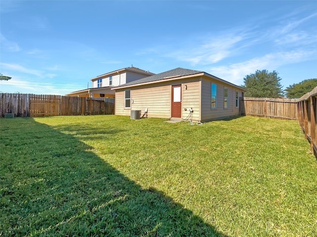 back of property featuring central AC unit and a yard