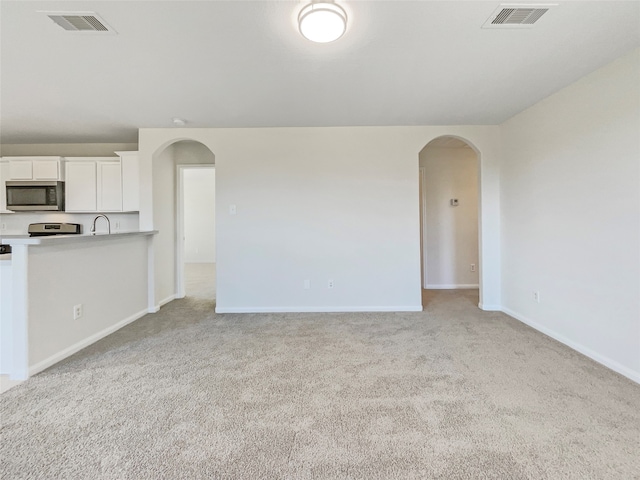 unfurnished living room with sink and light colored carpet