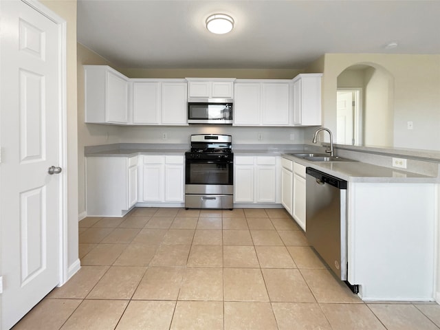 kitchen featuring kitchen peninsula, appliances with stainless steel finishes, sink, light tile patterned floors, and white cabinets