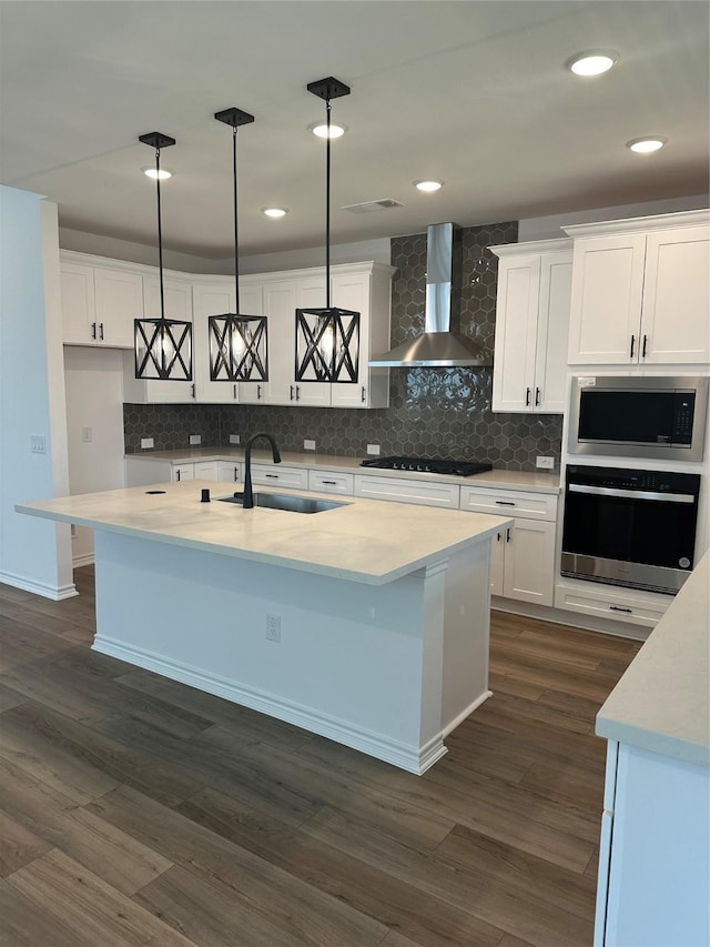 1253 Woodflower Dr, Katy, TX 77493 - kitchen with appliances with stainless steel finishes, a sink, wall chimney range hood, white cabinetry, and tasteful backsplash