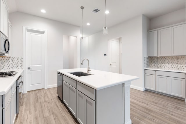 kitchen with decorative backsplash, light hardwood / wood-style floors, sink, and hanging light fixtures