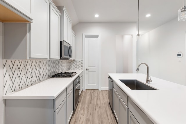 kitchen featuring sink, hanging light fixtures, tasteful backsplash, light hardwood / wood-style flooring, and appliances with stainless steel finishes