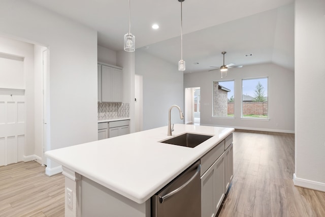 kitchen featuring light wood-type flooring, gray cabinetry, sink, dishwasher, and an island with sink